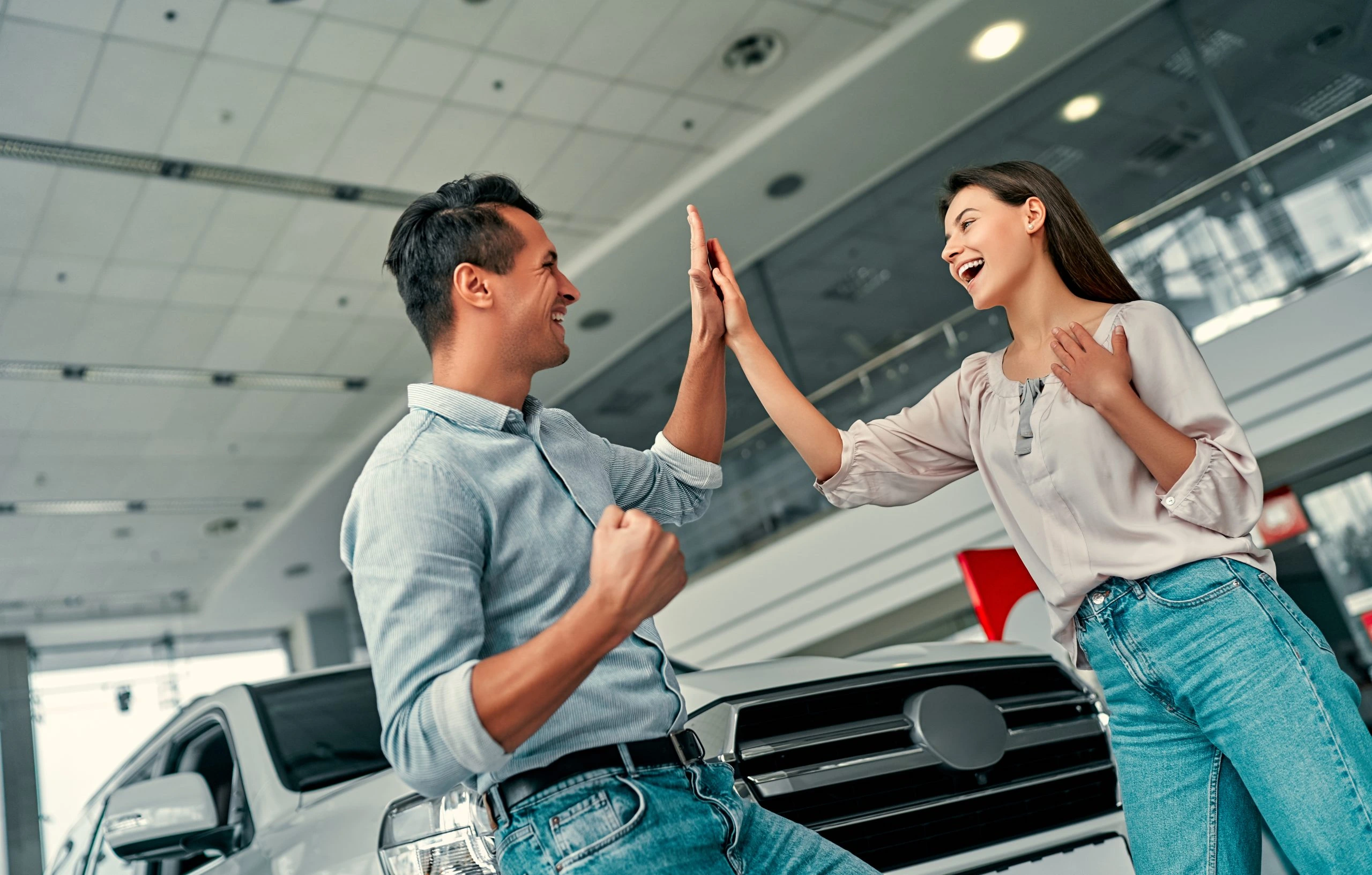 Couple heureux devant une voiture en concession