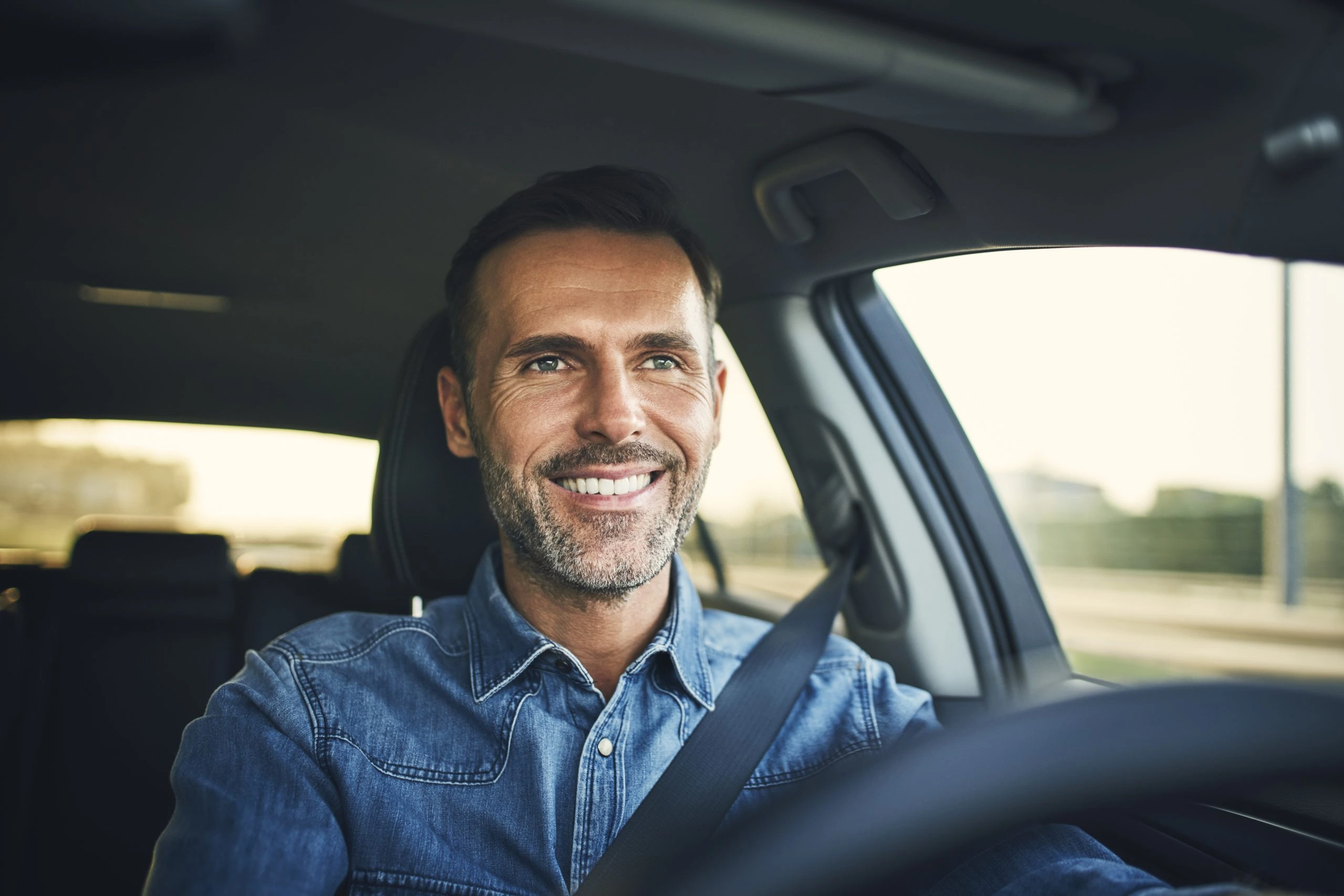 Conducteur souriant au volant de sa voiture